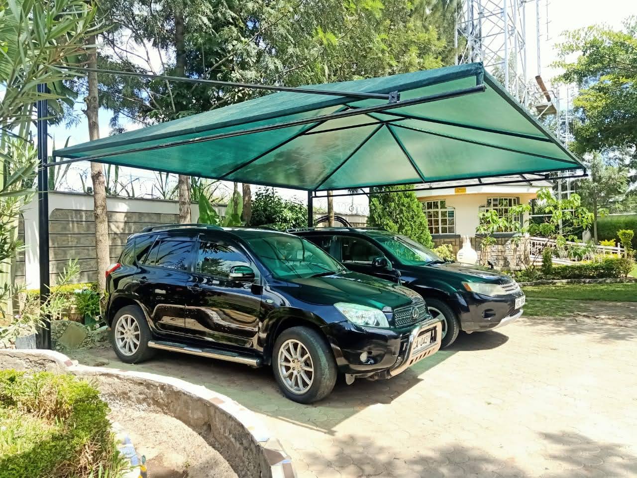 Green shade cloth car parking structure covering multiple SUVs