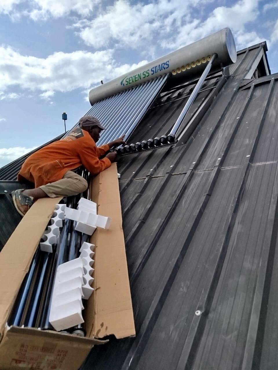 Technician installing a solar water heater on a client rooftop