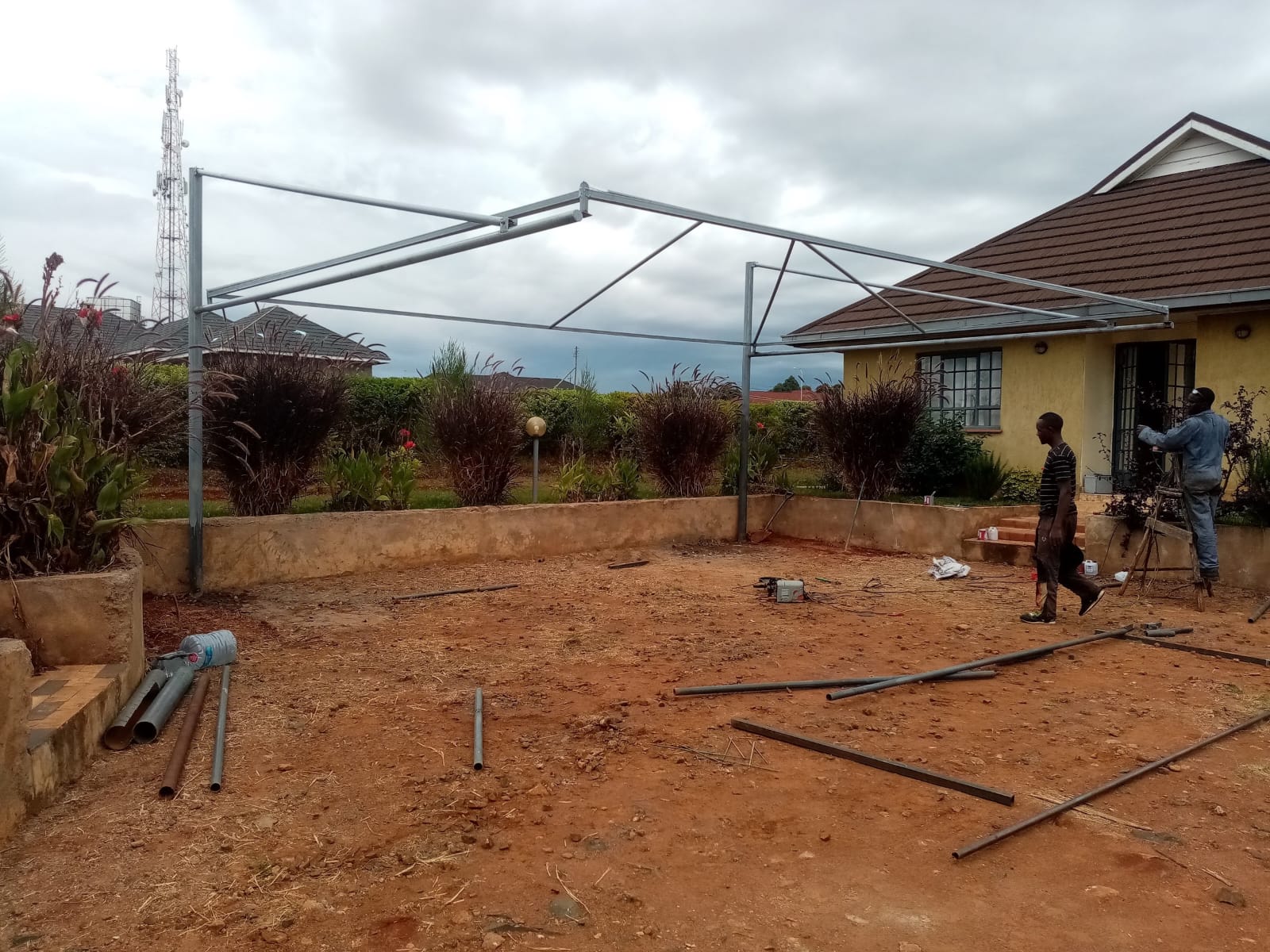 Bare galvanised steel cantilever frame for a car parking shade structure being erected in Kitale