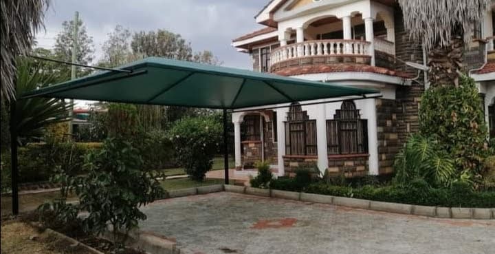 Green single-post cantilever car parking shade structure covering the driveway of an ornate double-storey residence in Lavington