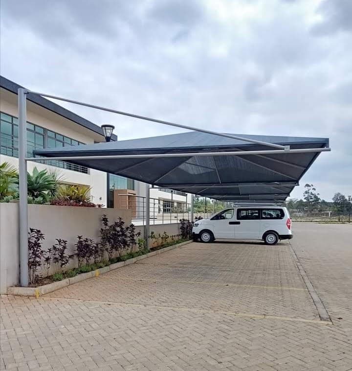 Dark tensile cantilever car parking shade structure covering visitor bays at a Nairobi office park
