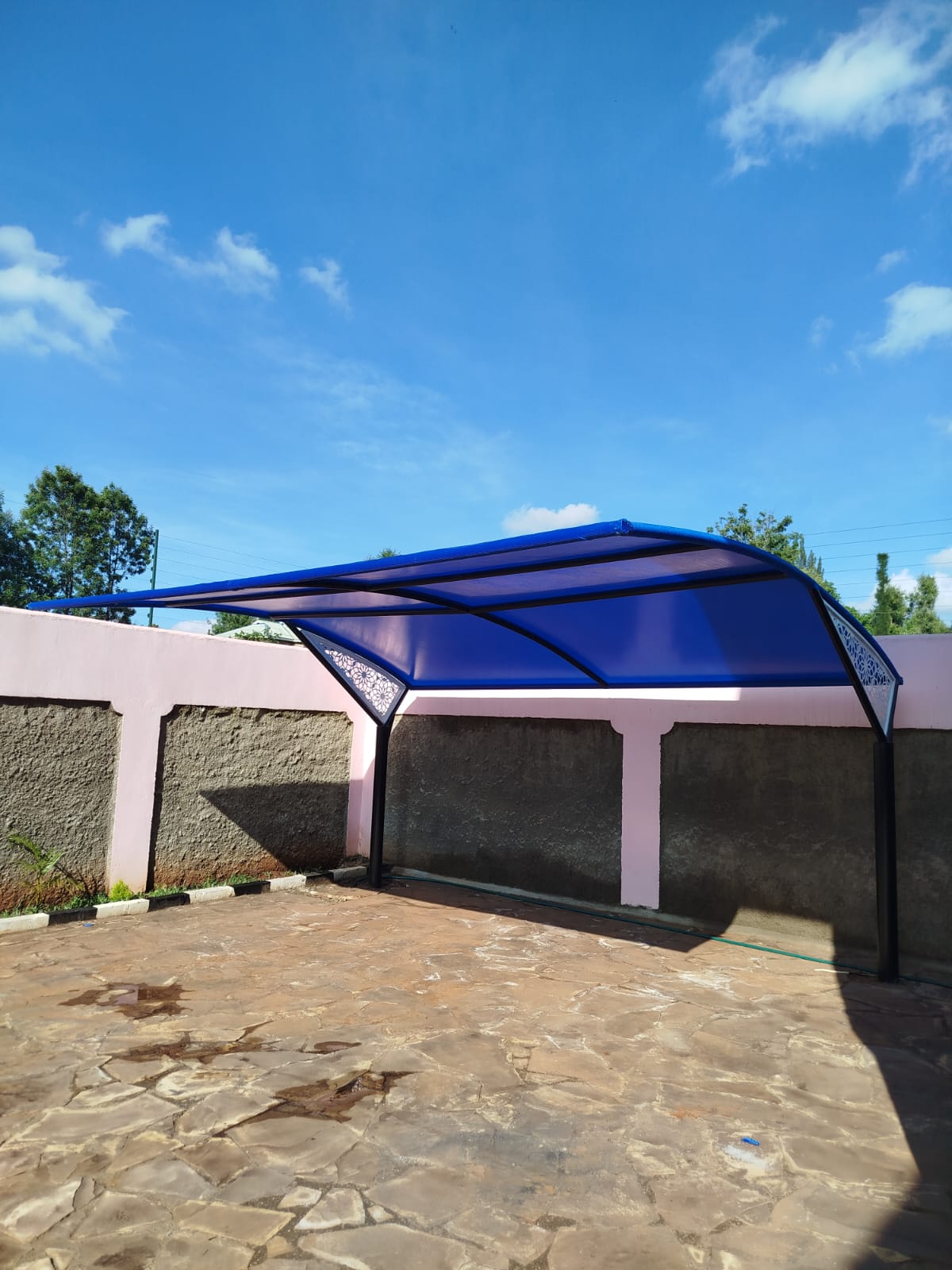 Finished blue cantilever car parking shade with decorative laser-cut floral panel wing tips at a Runda property, wide view