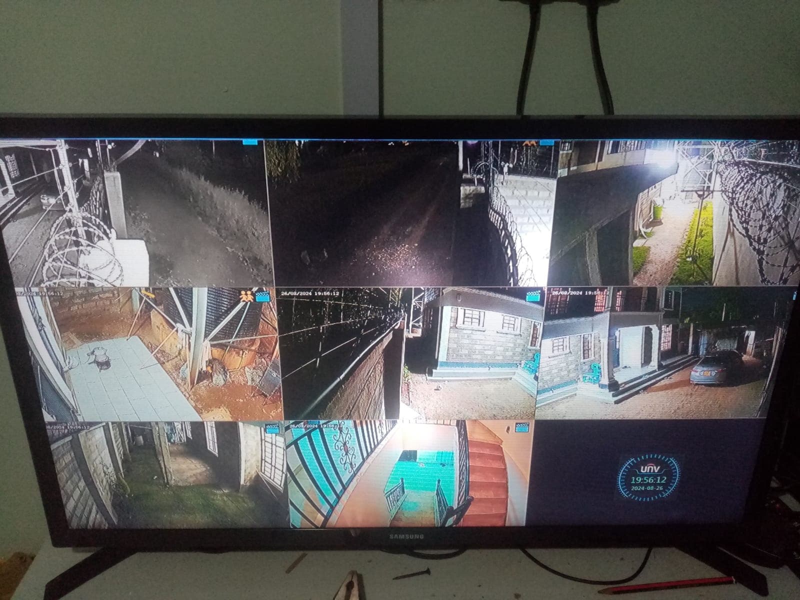Samsung monitor displaying a 9-camera Uniview CCTV split screen covering perimeter, courtyard, driveway, and staircase at a Kikuyu property