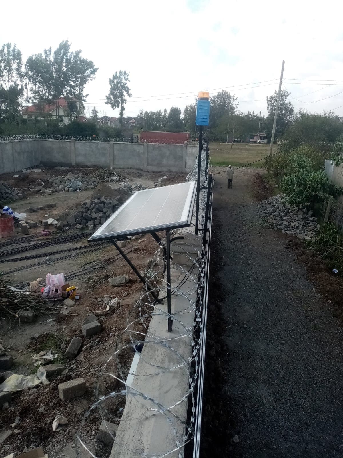 Solar panel mounted on a boundary wall post to power an electric fence energizer independently of mains electricity, Ruiru