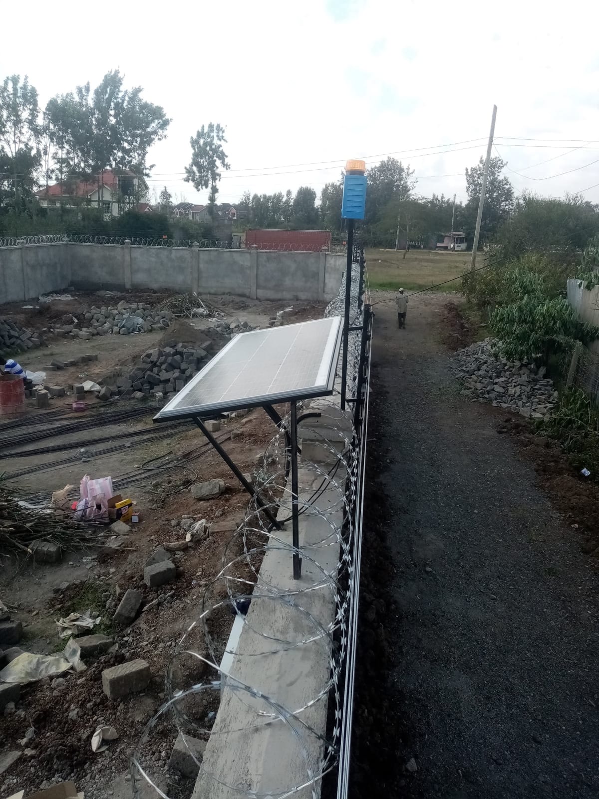 Solar panel mounted on a boundary wall post to power an electric fence energizer independently of mains electricity, Ruiru