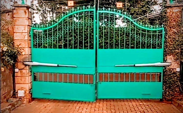 Ornate green double-leaf swing gate with dual arm motor actuators installed at a residential property in Machakos