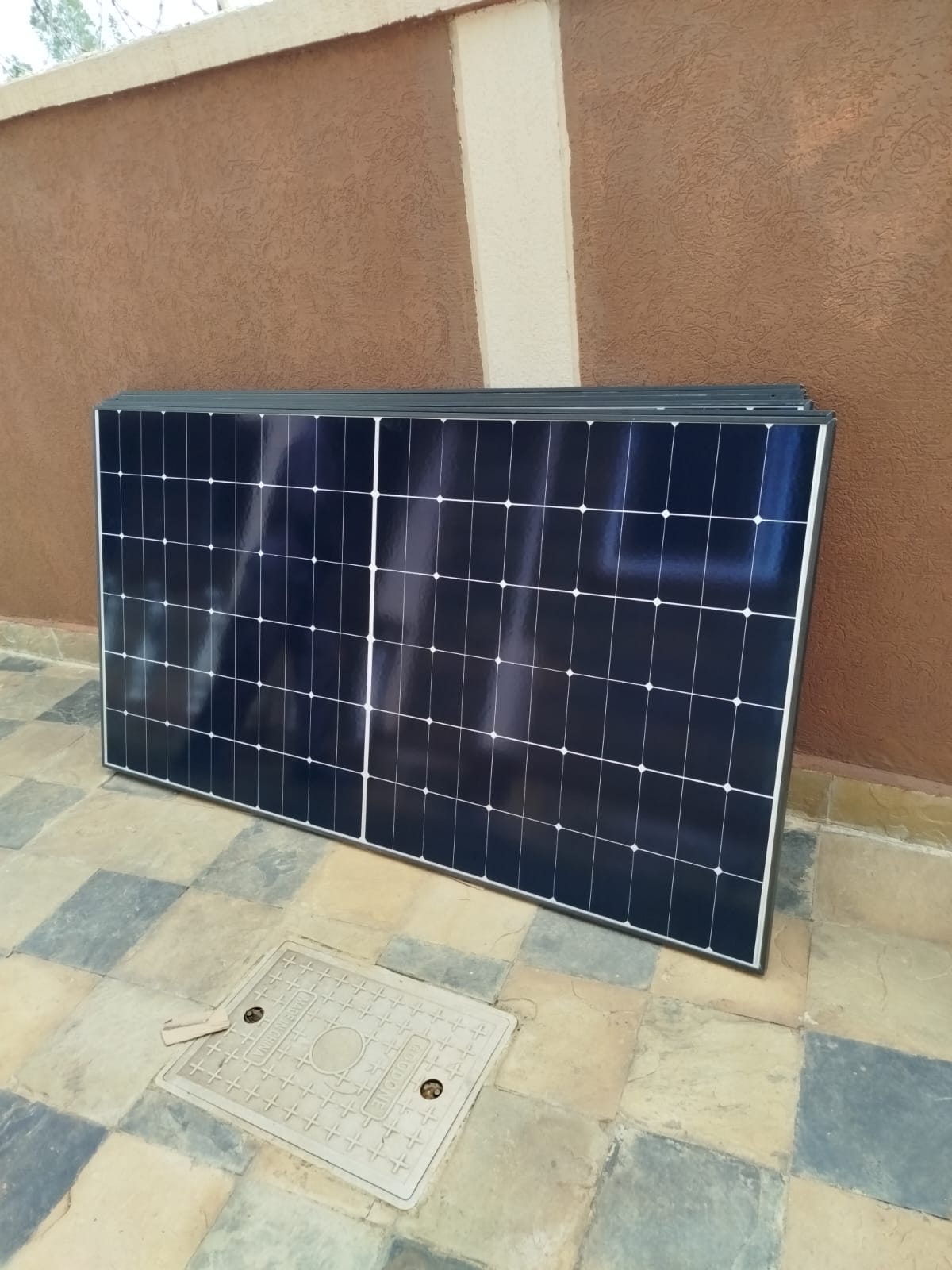 Solar panel resting against a boundary wall before rooftop mounting at a home in Mumias
