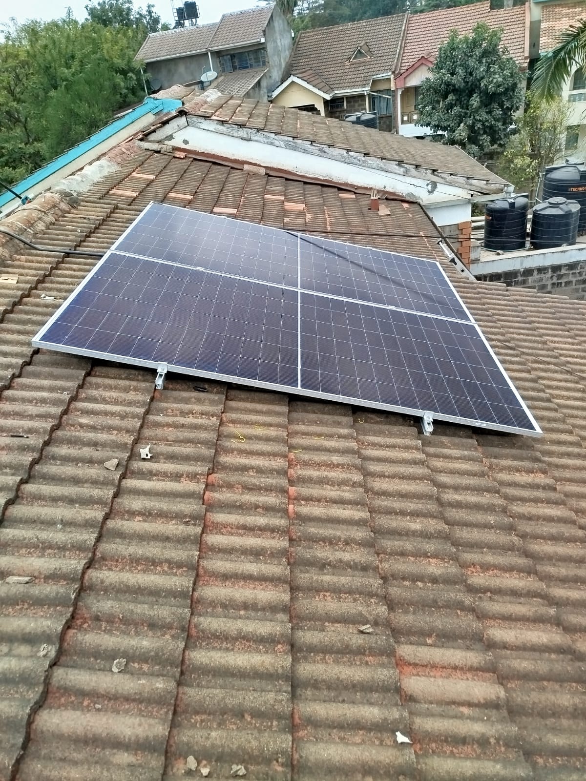 Single monocrystalline solar panel mounted on a tiled roof at a Nairobi apartment complex