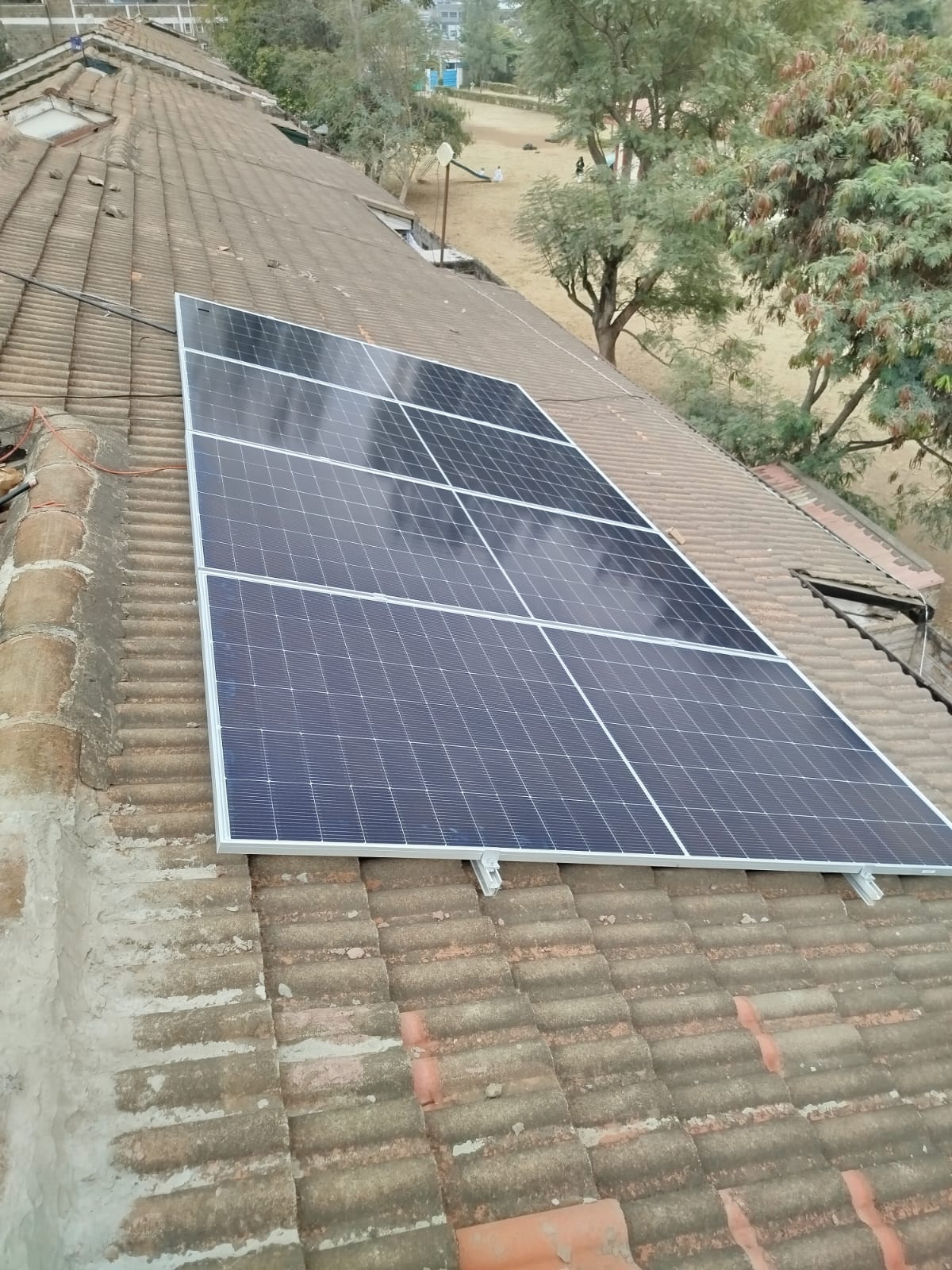 Full array of solar panels mounted on a tiled roof at a Nairobi apartment complex, playground and neighbouring buildings visible below