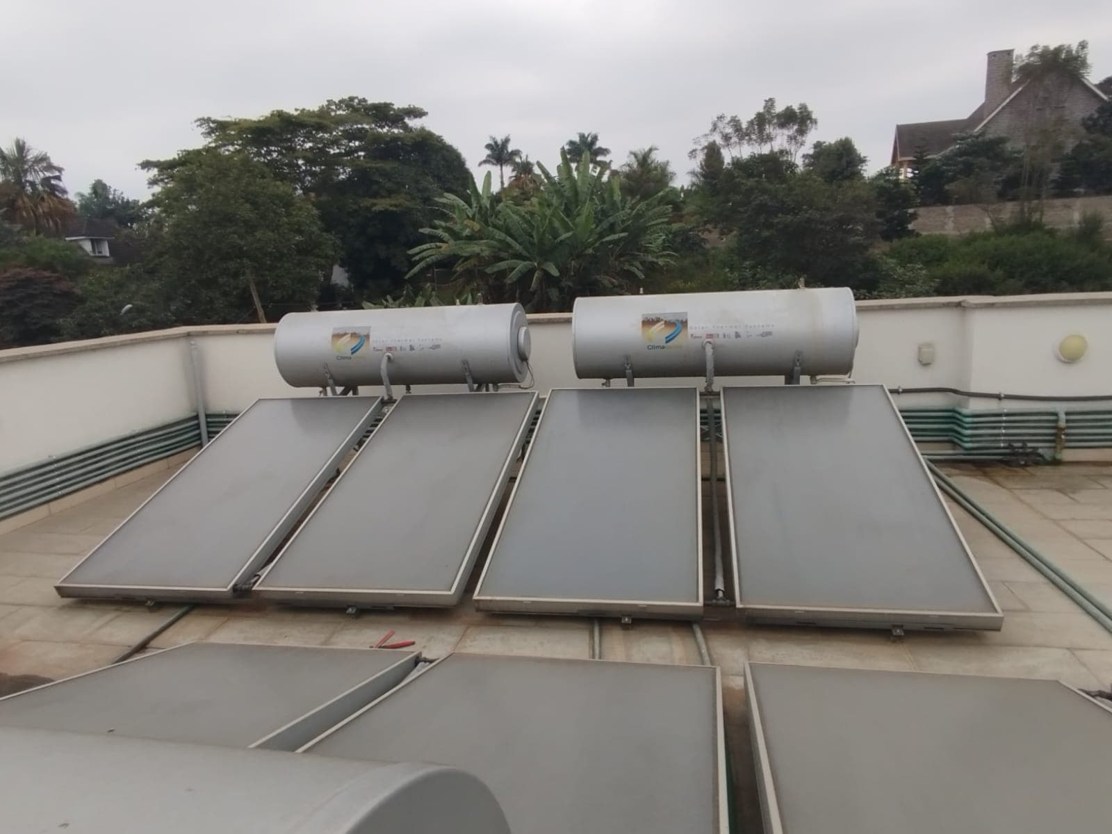 Multiple ClimaCento flat-plate solar water heater tanks and collector panels installed on a large institutional rooftop in Runda