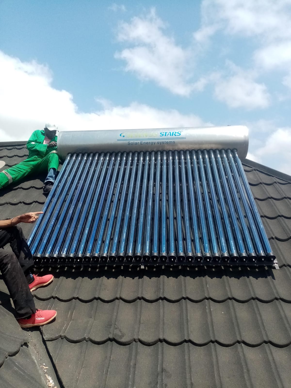 Close-up of a 300L evacuated-tube solar water heater collector tubes and stainless tank branded 'Seven Stars' on a tiled roof in Kiambu