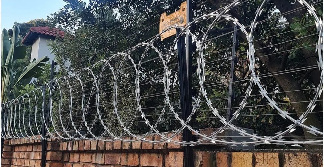Close-up of electric fence wiring and razor wire installed on a Kenyan perimeter wall